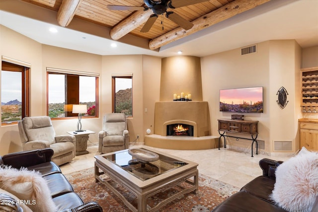 living room featuring beamed ceiling, ceiling fan, wooden ceiling, and a fireplace