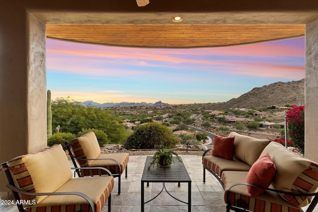 balcony at dusk featuring outdoor lounge area, a mountain view, and a patio