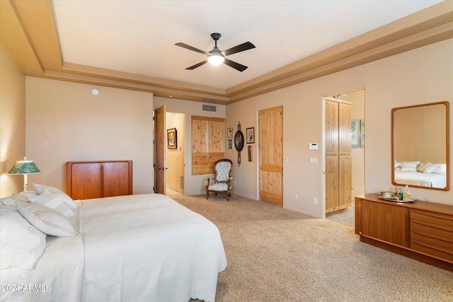 bedroom with a tray ceiling, ceiling fan, and light colored carpet