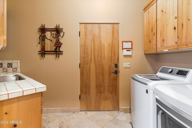 washroom featuring cabinets, light tile patterned floors, washer and clothes dryer, and sink