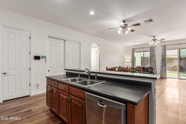 kitchen with dark countertops, visible vents, stainless steel dishwasher, arched walkways, and a sink