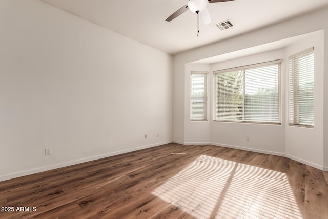 spare room featuring wood finished floors, visible vents, and baseboards