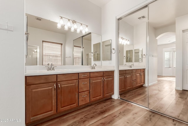 full bath with double vanity, visible vents, wood finished floors, and a sink