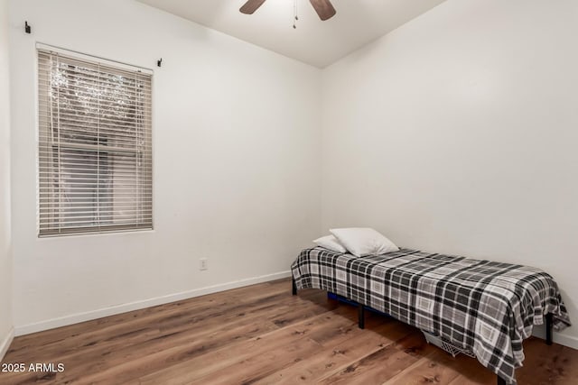 bedroom featuring a ceiling fan, baseboards, and wood finished floors