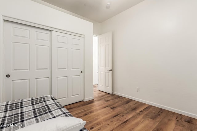 unfurnished bedroom featuring a closet, baseboards, and wood finished floors