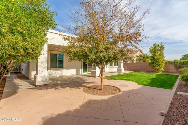 exterior space featuring a patio, fence, a front lawn, and stucco siding