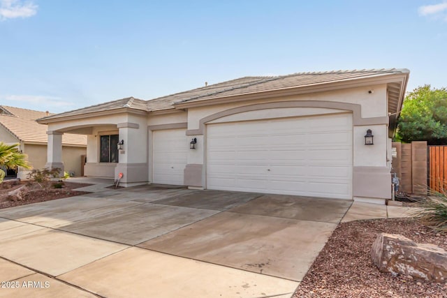 view of front of home with stucco siding, driveway, fence, a garage, and a tiled roof