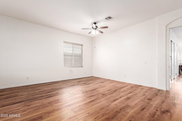 spare room featuring a ceiling fan, wood finished floors, visible vents, and baseboards