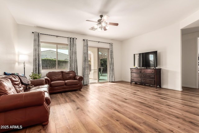 living room with ceiling fan, baseboards, and wood finished floors