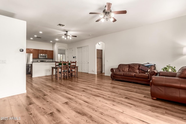 living area featuring visible vents, recessed lighting, arched walkways, ceiling fan, and light wood-style floors