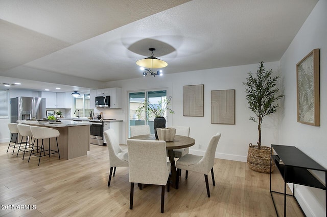 dining area featuring sink, light hardwood / wood-style flooring, and an inviting chandelier