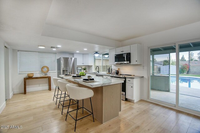 kitchen with white cabinets, appliances with stainless steel finishes, a center island, and sink