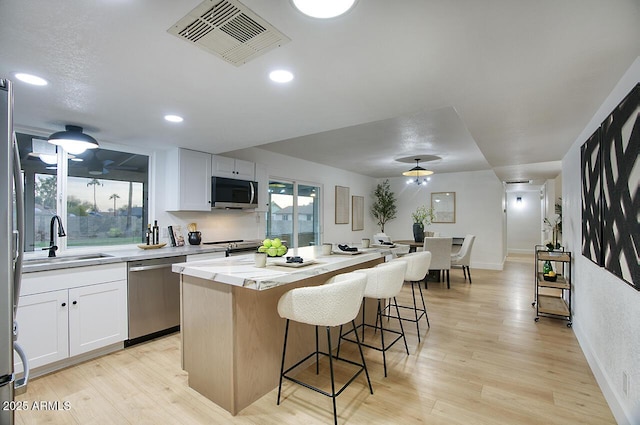 kitchen with sink, white cabinets, a center island, and appliances with stainless steel finishes