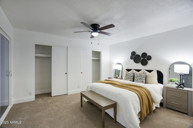 carpeted bedroom featuring multiple closets, a textured ceiling, and ceiling fan