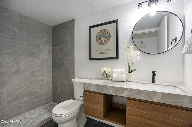 bathroom featuring a textured ceiling, tile patterned floors, vanity, toilet, and a tile shower