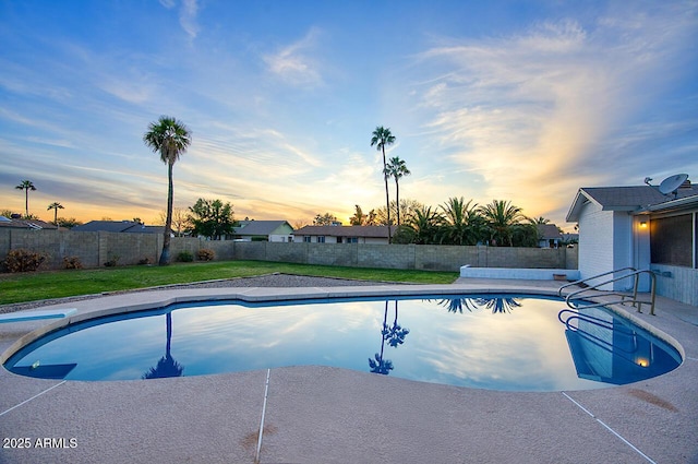 pool at dusk featuring a diving board and a lawn