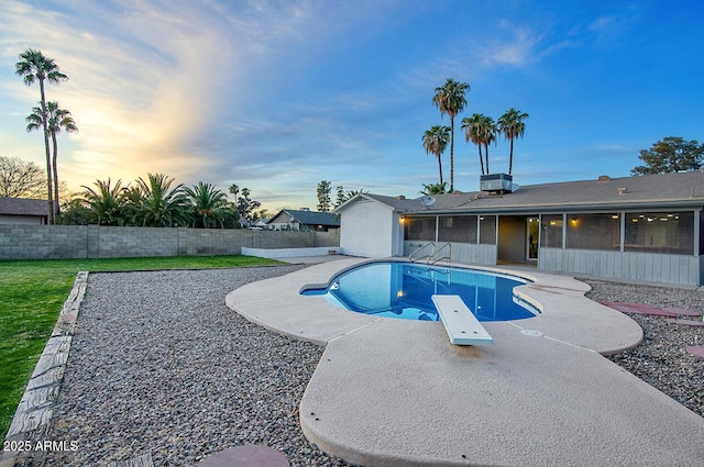 pool at dusk featuring a diving board, a patio, central AC unit, and a sunroom