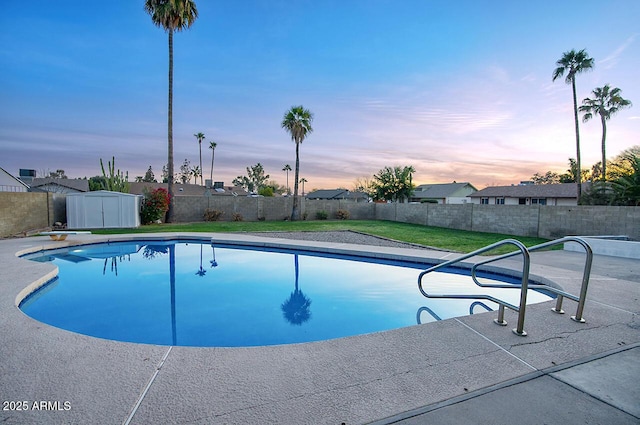 pool at dusk with a diving board and a storage unit