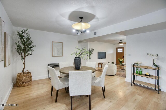 dining space featuring light wood-type flooring and a notable chandelier