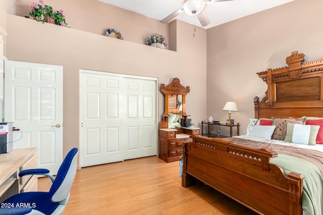 bedroom with light hardwood / wood-style flooring, a closet, a high ceiling, and ceiling fan