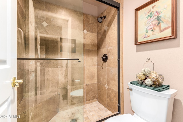 bathroom featuring a shower with door and toilet