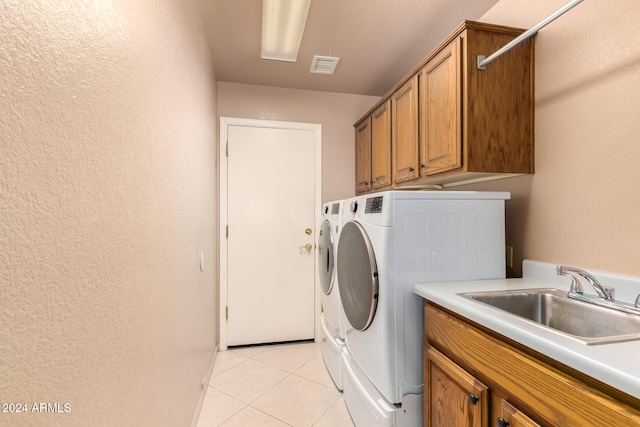 laundry area featuring cabinets, light tile patterned flooring, sink, and washing machine and dryer