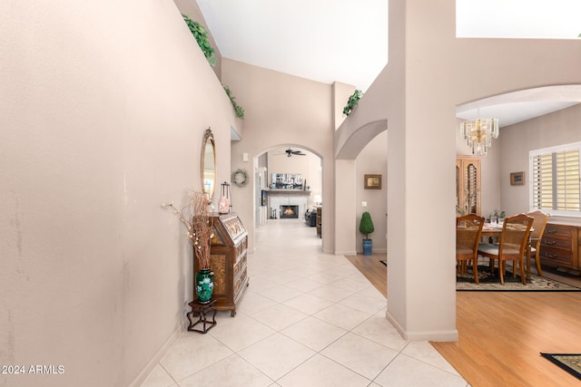 hall with light hardwood / wood-style floors, high vaulted ceiling, and a chandelier