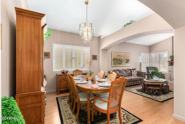 dining area featuring an inviting chandelier, vaulted ceiling, and light hardwood / wood-style floors