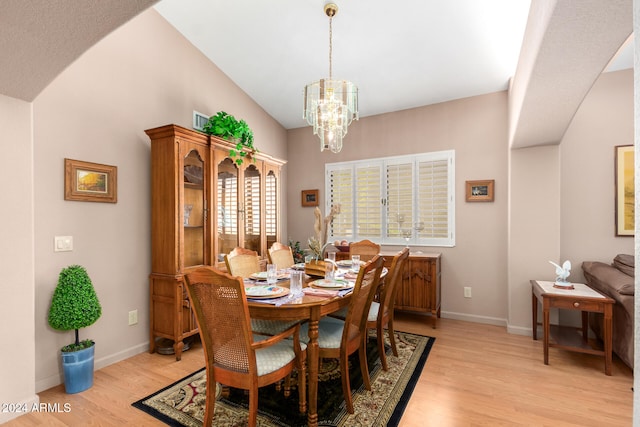 dining space with lofted ceiling, light hardwood / wood-style flooring, and a notable chandelier