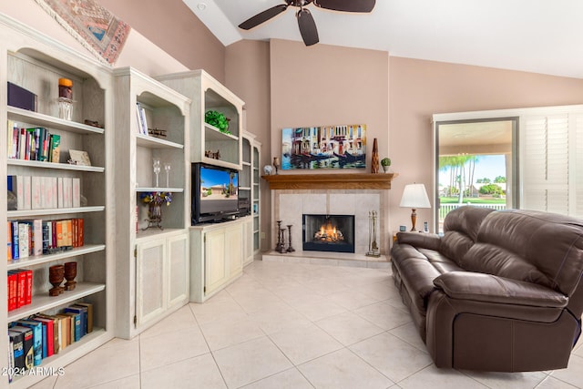 living room featuring a tiled fireplace, vaulted ceiling, light tile patterned floors, and ceiling fan