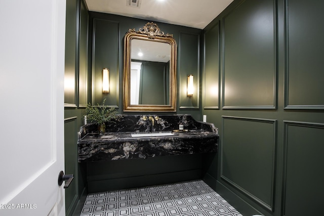 bathroom with a decorative wall, vanity, and visible vents