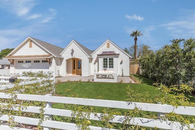 view of front of property featuring brick siding, a garage, fence private yard, and a front lawn