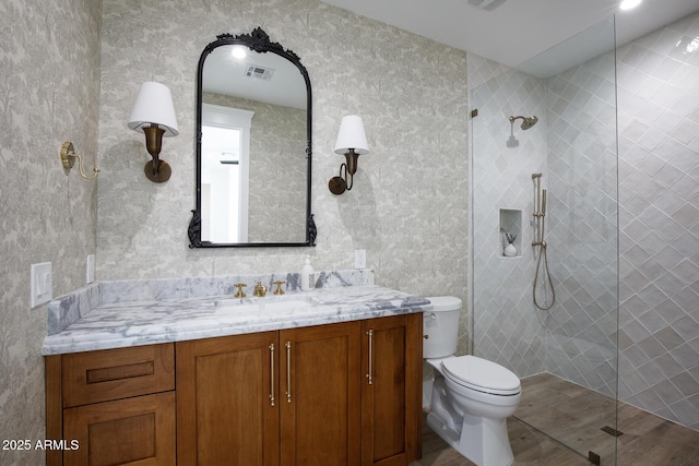 bathroom with vanity, toilet, a walk in shower, and visible vents