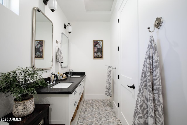 full bathroom with double vanity, baseboards, and a sink