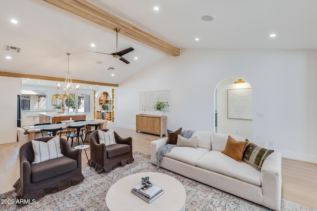 living room featuring arched walkways, visible vents, vaulted ceiling with beams, and light wood-style floors