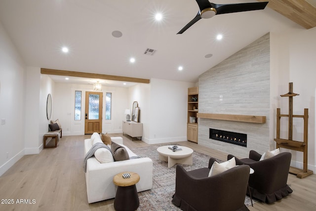 living area with light wood finished floors, visible vents, vaulted ceiling with beams, a large fireplace, and recessed lighting