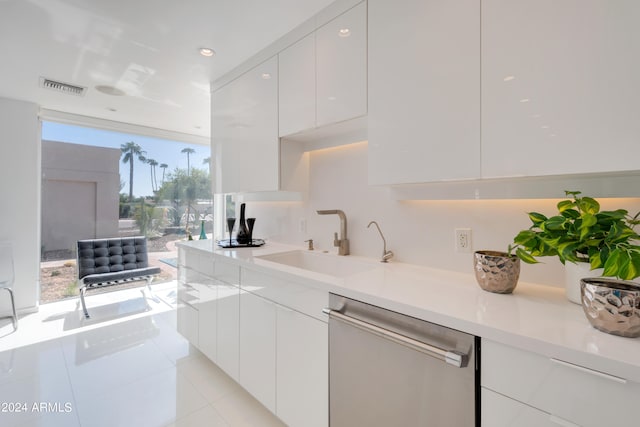 kitchen with stainless steel dishwasher, light tile patterned flooring, sink, and white cabinets