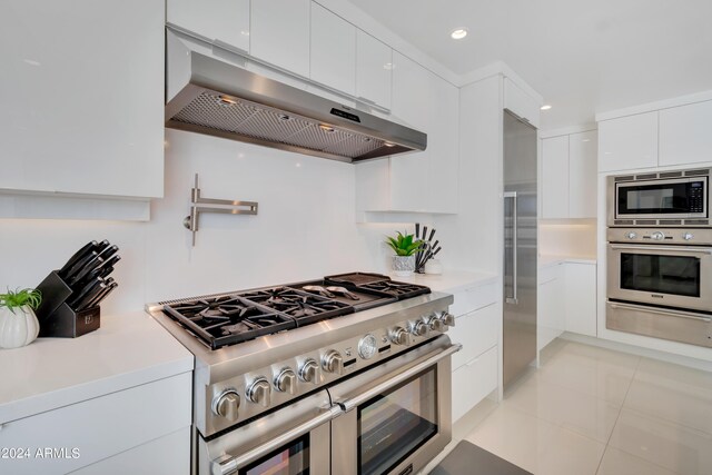 kitchen featuring ventilation hood, white cabinets, stainless steel appliances, and light tile patterned floors