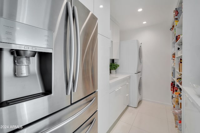 clothes washing area featuring stacked washer and dryer and light tile patterned flooring