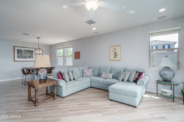 living room with ceiling fan with notable chandelier and light hardwood / wood-style floors