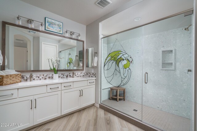 bathroom with dual vanity, an enclosed shower, and hardwood / wood-style flooring