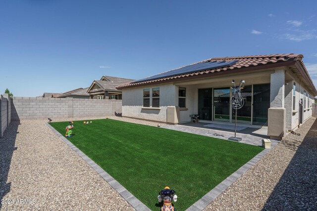 back of house with solar panels, a patio, and a yard