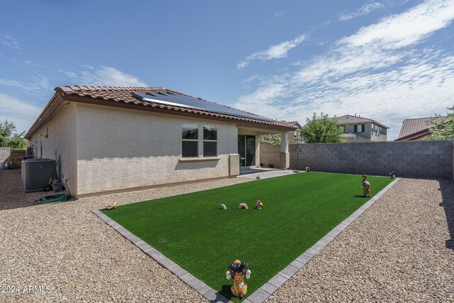 back of property with solar panels, cooling unit, and a patio area