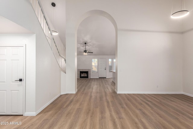 1405 N Jamaica Way, Gilbert, AZ 85234 - unfurnished living room with a ceiling fan, light wood finished floors, stairs, a fireplace, and arched walkways