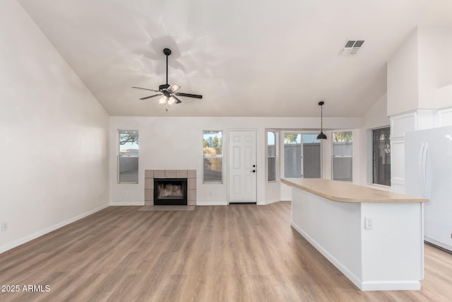 1405 N Jamaica Way, Gilbert, AZ 85234 - unfurnished living room featuring lofted ceiling, light wood-style floors, a ceiling fan, and a tiled fireplace