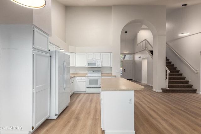 1405 N Jamaica Way, Gilbert, AZ 85234 - kitchen featuring white appliances, light countertops, light wood-style flooring, a kitchen island, and white cabinetry