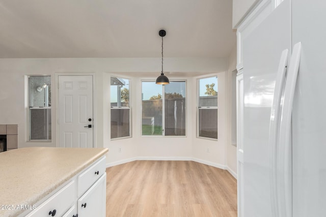 1405 N Jamaica Way, Gilbert, AZ 85234 - kitchen with freestanding refrigerator, light wood-style flooring, white cabinets, decorative light fixtures, and light countertops