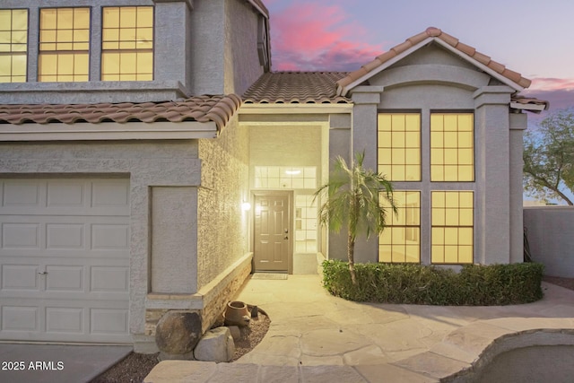 1405 N Jamaica Way, Gilbert, AZ 85234 - exterior entry at dusk featuring a tile roof, stucco siding, and a garage