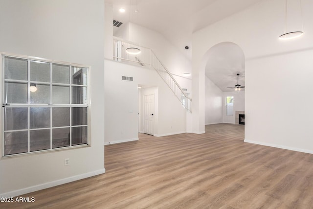 1405 N Jamaica Way, Gilbert, AZ 85234 - unfurnished living room with a ceiling fan, wood finished floors, high vaulted ceiling, arched walkways, and stairway