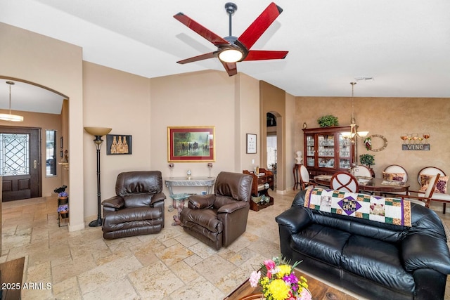 15740 N 91st Dr, Peoria, AZ 85382 - living room featuring arched walkways, stone tile flooring, a chandelier, a ceiling fan, and baseboards